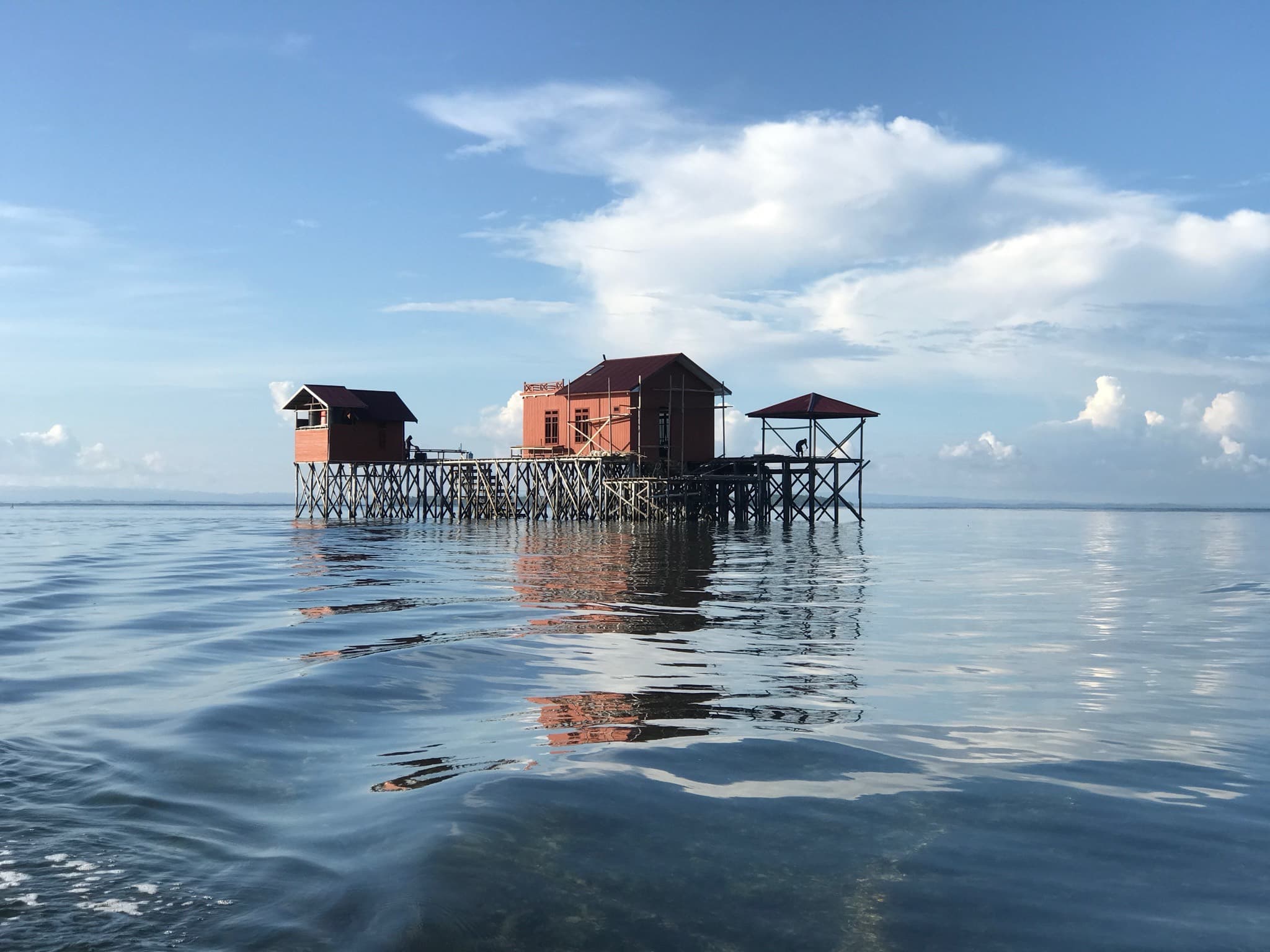 Villa panggung kayu merah ASA Miang berdiri di atas laut tenang, terlihat dari permukaan air